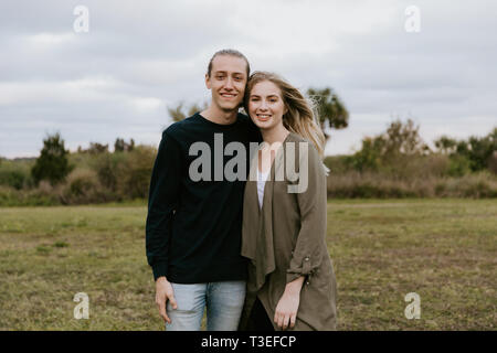 Junges Paar in der Liebe, die in einem großen offenen Im freien Feld im Frühling Hände halten und Lachen Stockfoto