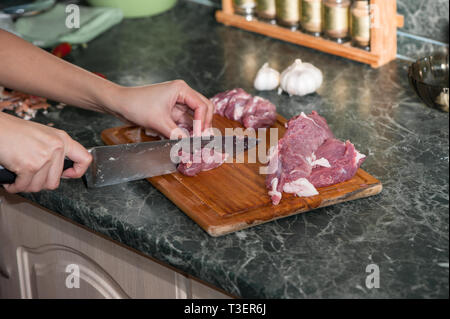 Fleisch mit Messer auf Schneidebrett in der Küche Stockfoto