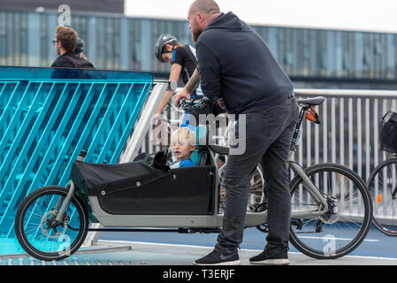 Eine dänische Vater mit seinem kleinen Sohn in einem cargo bike Warten, bis die Inderhavnsbroen (Inner Harbour Bridge) in Kopenhagen zu öffnen. Stockfoto