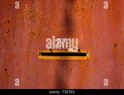 Alte rot lackiertem Metall Tür mit der Nummer 15 Fraktionen zwei und mail Loch mit orange Edge Stockfoto