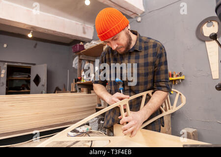 Home Reparatur Konzepte, hautnah. Handwerk Tischlerei. Cabinet-maker Hände bohren ein Holzbrett mit Turn-Schraube auf dem Arbeitstisch in der worksho Stockfoto