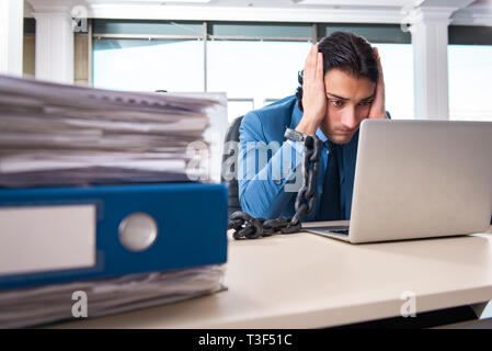 Verkettete männliche Angestellte mit übermäßiger Arbeit unzufrieden Stockfoto