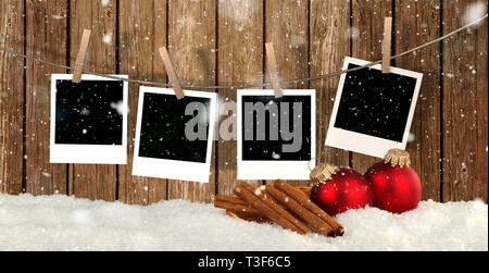 Leere instant Fotos hängen an der Wäscheleine vor Holz- Hintergrund mit Schnee und Weihnachten Kugeln - Weihnachten Hintergrund Stockfoto