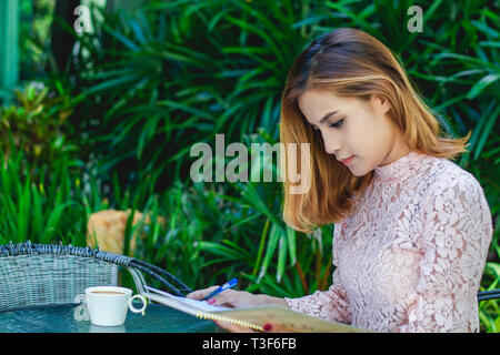 Asiatische Frau Menü öffnen für die Bestellung im Kaffee Cafe und Restaurant und für die glückliche Zeit lächelnd Stockfoto