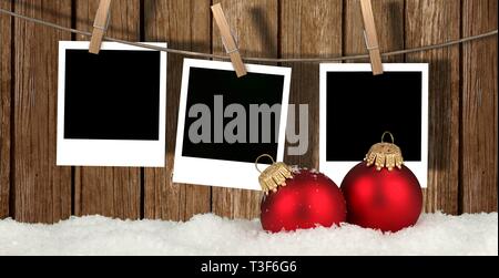 Leere instant Fotos hängen an der Wäscheleine vor Holz- Hintergrund mit Schnee und Weihnachten Kugeln - Weihnachten Hintergrund Stockfoto