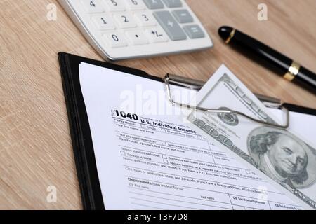 1040 Steuerformular - individuelle Einkommensteuererklärung Formular 1040 liegt in der Nähe von hundert Dollar auf einem Tisch Stockfoto