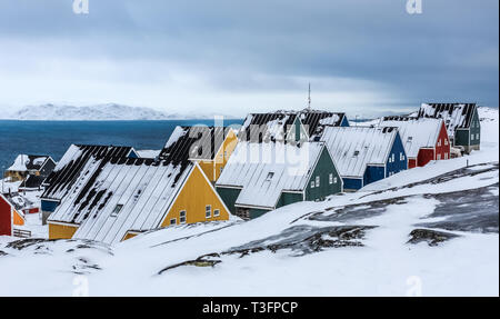 Gelbe, blaue, rote und grüne Inuit Häuser schneebedeckt am Fjord der Stadt Nuuk, Grönland Stockfoto