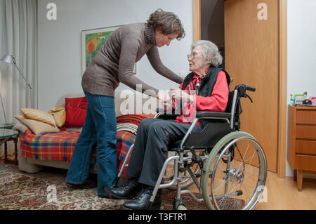 Junge Frau kümmert sich um die ältere Frau sitzt im Rollstuhl Stockfoto