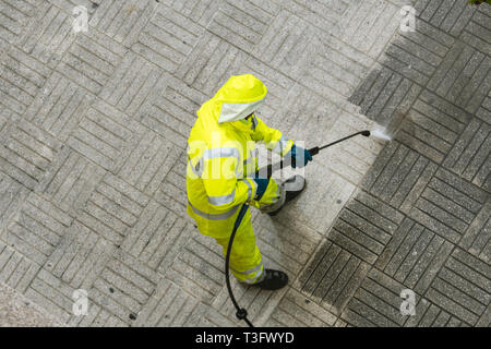 Blick von oben auf ein Arbeiter die Straße Gehweg mit Hochdruck Wasserstrahl reinigen. Öffentliche Wartungskonzept Stockfoto