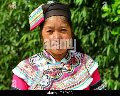 Reifen Miao Frau (chinesische ethnische Minderheit) trägt eine bunte traditionelle ethnische Kostüm und Lächeln für die Kamera. Stockfoto