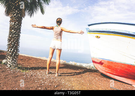 Zurück Blick auf eine junge Frau, die ihre Hände heben und bewundern Sie die Aussicht auf das Meer aus dem Hügel - Schöne Mädchen Spaß haben Reisen Stockfoto