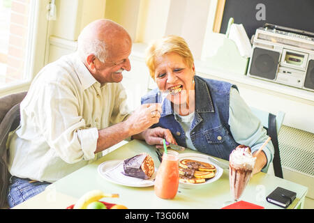 Happy Senioren Paar essen Pfannkuchen in einer Bar Restaurant - Rentner Spaß Mittagessen gemeinsam genießen - Konzept der älteren Rentner Stockfoto