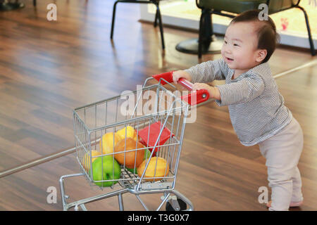 Asiatische niedlichen Baby drücken Warenkorb Spielzeug Stockfoto