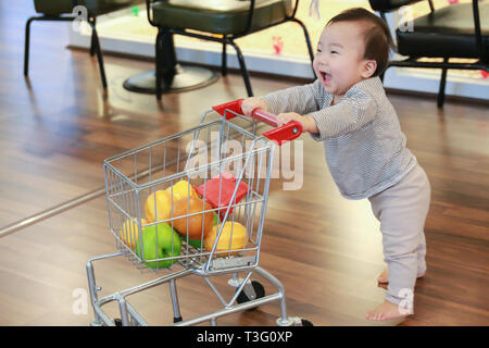 Asiatische niedlichen Baby drücken Warenkorb Spielzeug Stockfoto