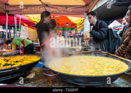 Ein Mann kauft Lebensmittel aus einer Paella essen in Portibello Road, London, UK Abschaltdruck Stockfoto