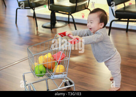 Asiatische niedlichen Baby drücken Warenkorb Spielzeug Stockfoto