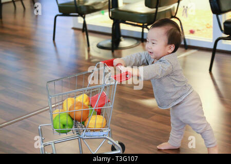 Asiatische niedlichen Baby drücken Warenkorb Spielzeug Stockfoto