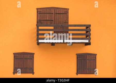 Balkon aus Holz mit Türen und Fenstern auf orange Wand Hintergrund minimalen Begriff. Stockfoto