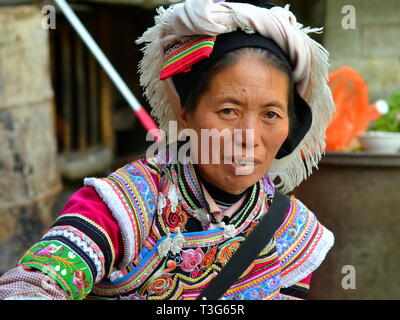 Ältere Miao markt Frau (chinesische ethnische Minderheit) trägt einen farbenfrohen traditionellen ethnischen Kleid und posiert für die Kamera. Stockfoto