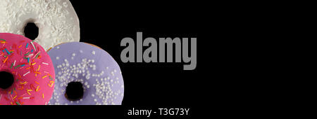 Drei verschiedenen Donuts auf schwarzem Hintergrund. Schließen sie isoliert. Banner. Stockfoto