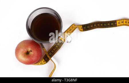 Abnehmen mit Tee und Obst, eine Tasse mit Tee und einem Maßband und einem köstlichen roten Apfel auf weißem Hintergrund Stockfoto