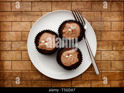Eine weiße Platte mit 3 Schokolade fee Kuchen, und eine Gabel auf einem hölzernen Hintergrund, Schuß von oben Stockfoto