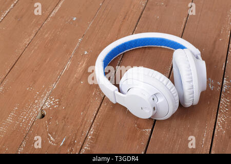 Musikinstrumente - Weiß Blau kabelloser Kopfhörer auf einer hölzernen Hintergrund. Stockfoto