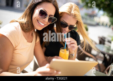 Freunde haben eine großartige Zeit im Cafe. Frauen lächeln und Saft trinken und gemeinsam genießen Stockfoto