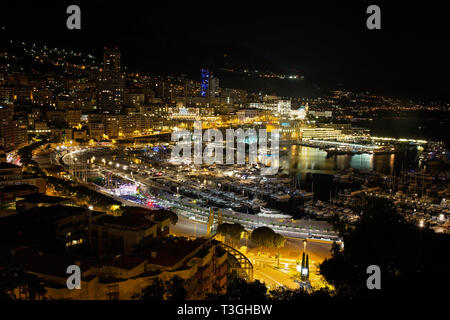Panorama von Monte Carlo in der Nacht aus dem Dorf von Monaco mit Port Hercules. Gebäude mit Beleuchtung und Yachten im Hafen Luftbild Ansicht von oben Stockfoto