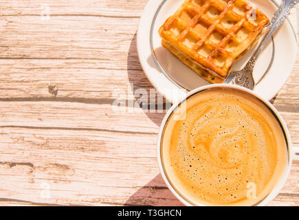 Weiche Wiener Waffel auf einen Teller, eine Tasse Kaffee auf einer hölzernen Hintergrund, Ansicht von oben, Kopieren, flach Stockfoto