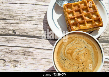 Weiche Wiener Waffel auf einen Teller, eine Tasse Kaffee auf einer hölzernen Hintergrund, Ansicht von oben, Kopieren, flach Stockfoto