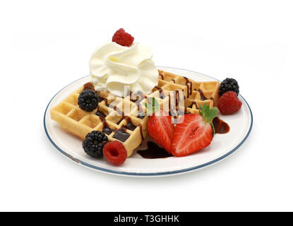 Frische belgische Waffeln mit Erdbeeren, Obst und Beeren und Sahne auf einem Schild auf weißem Hintergrund Stockfoto