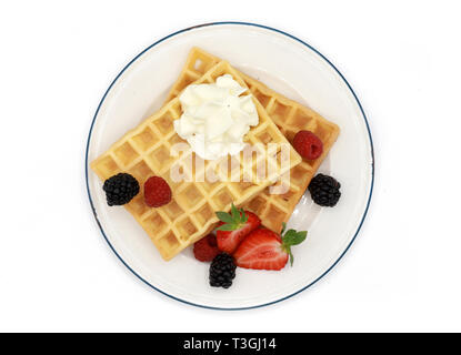 Frische belgische Waffeln mit Erdbeeren, Obst und Beeren und Sahne auf einem Schild auf weißem Hintergrund Stockfoto