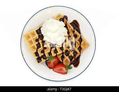 Frische belgische Waffeln mit Schokoladensauce, Erdbeeren und Schlagsahne auf einem Schild auf weißem Hintergrund Stockfoto