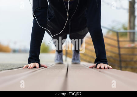 Sportliche junge Frau, Plank Übung für Bauchmuskulatur und Trizeps im Freien Stockfoto