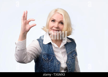 Ältere Frau, kleine Zeichen mit den Fingern Stockfoto
