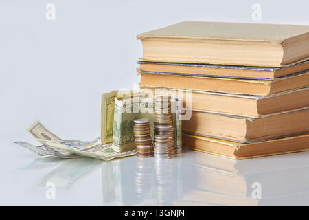 Finanzielle Bildung Konzept - Geld: Rechnungen, Münzen, alte Bücher auf einem Glastisch. Stockfoto