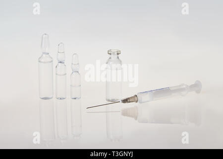 Medizinische Ampullen zur Injektion mit einer Spritze und Ampullen auf grauem Hintergrund Stockfoto