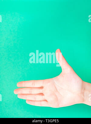 Weibliche hand auf isolierte türkis grün Hintergrund. Stretch Arm die Hand zur Begrüßung. Hand bereit für Handshaking. Stockfoto