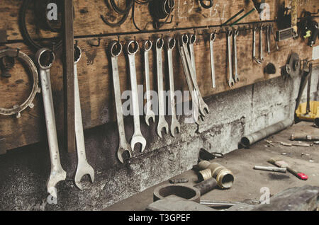 Alte Schlüssel hängen über der Tabelle in der Werkstatt Stockfoto
