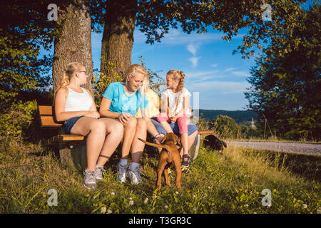 Familie ruht auf der Bank bei einem langen Spaziergang im Sommer Stockfoto