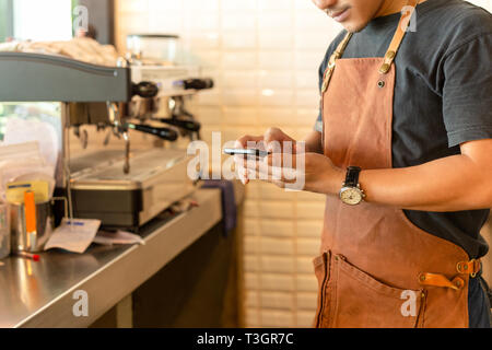 Barista Kontrolle Handy im Coffee Shop. Stockfoto
