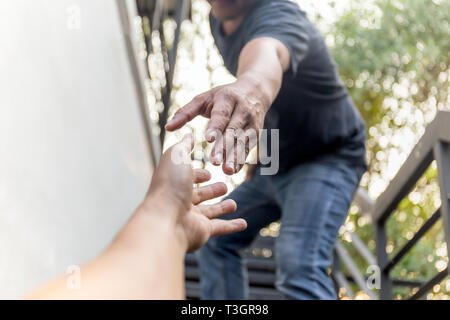 Hilfe Konzept Hände greifen sich gegenseitig mit bokeh Hintergrund zu helfen. Stockfoto