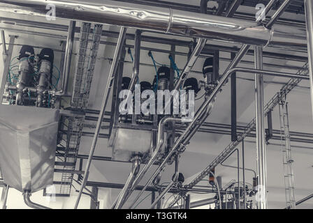 Rohre aus rostfreiem Stahl in der Fabrik. Bau auf die Nahrungsmittelproduktion, abstrakte Industrie Hintergrund. Stockfoto