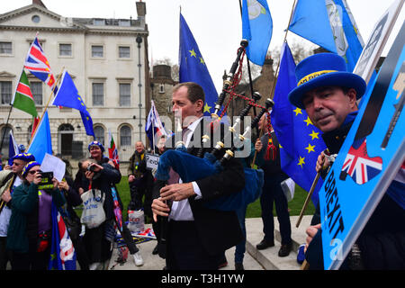 Alastair Campbell spielt Dudelsack durch Demonstranten außerhalb des Houses of Parliament in Westminster umgeben. Stockfoto