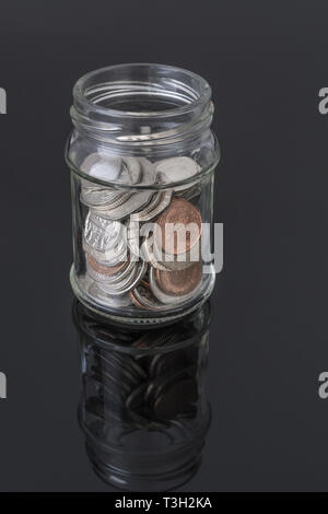 Glas Glas mit UK-Münzen - als Metapher für die persönlichen Ersparnissen, regnerischer Tag sparen, Altersvorsorge Topf, Topf. Stockfoto