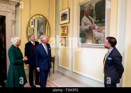 Der Prinz von Wales (dritter von links) präsentiert ein neues Portrait von sich selbst durch lokale Künstler Gareth Reid (rechts) bei einem Besuch in Hillsborough Schloss und Gärten mit der Herzogin von Cornwall (links), vor der Öffentlichkeit Wiedereröffnung des offiziellen Wohnsitz. Auch dargestellt Bill Montgomery (zweiter von links). Stockfoto