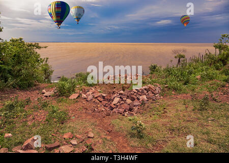 Heißluftballons über den Rio Parana, ein Grenzfluss zwischen Paraguay und Argentinien bei der blauen Stunde. Stockfoto