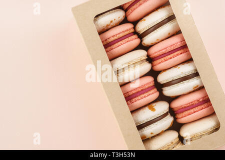 Bunte macarons in einer Geschenkbox bei monochromen rosa Hintergrund. Ansicht von oben. Stockfoto
