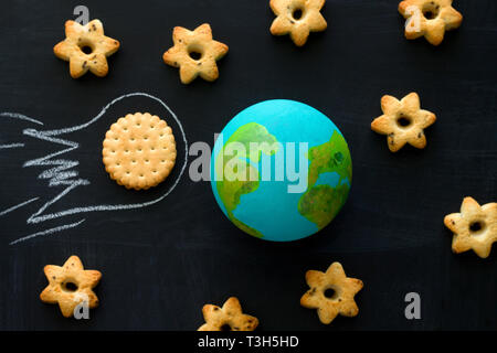 Ansicht von oben handgefertigte Modell der Erde, cookie Meteoriten und Kekse in Form von Sternen auf dem Schwarzen Brett, Raumfahrt und Astronomie Konzept Stockfoto